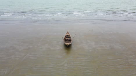 aerial tilt shot of a lone wooden boat on calm sea beach of bangladesh