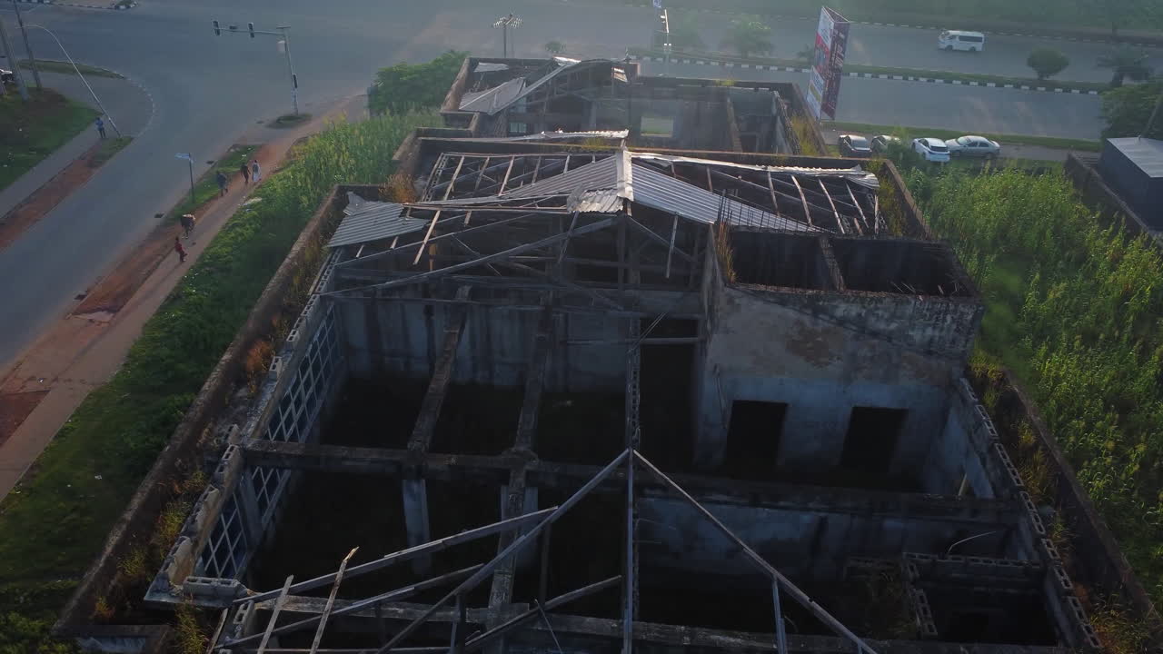 High angle view of a collapsed rooftop of a large structure in a suburban neighborhood. People walk around the pavement in the city of Abuja in Nigeria