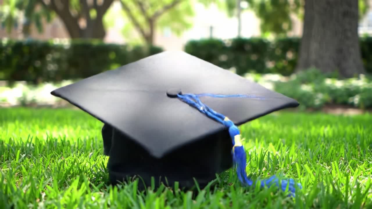 A graduation cap rests on lush green grass, symbolizing academic success and new beginnings. This moment captures the joy and pride of graduates during commencement ceremonies.