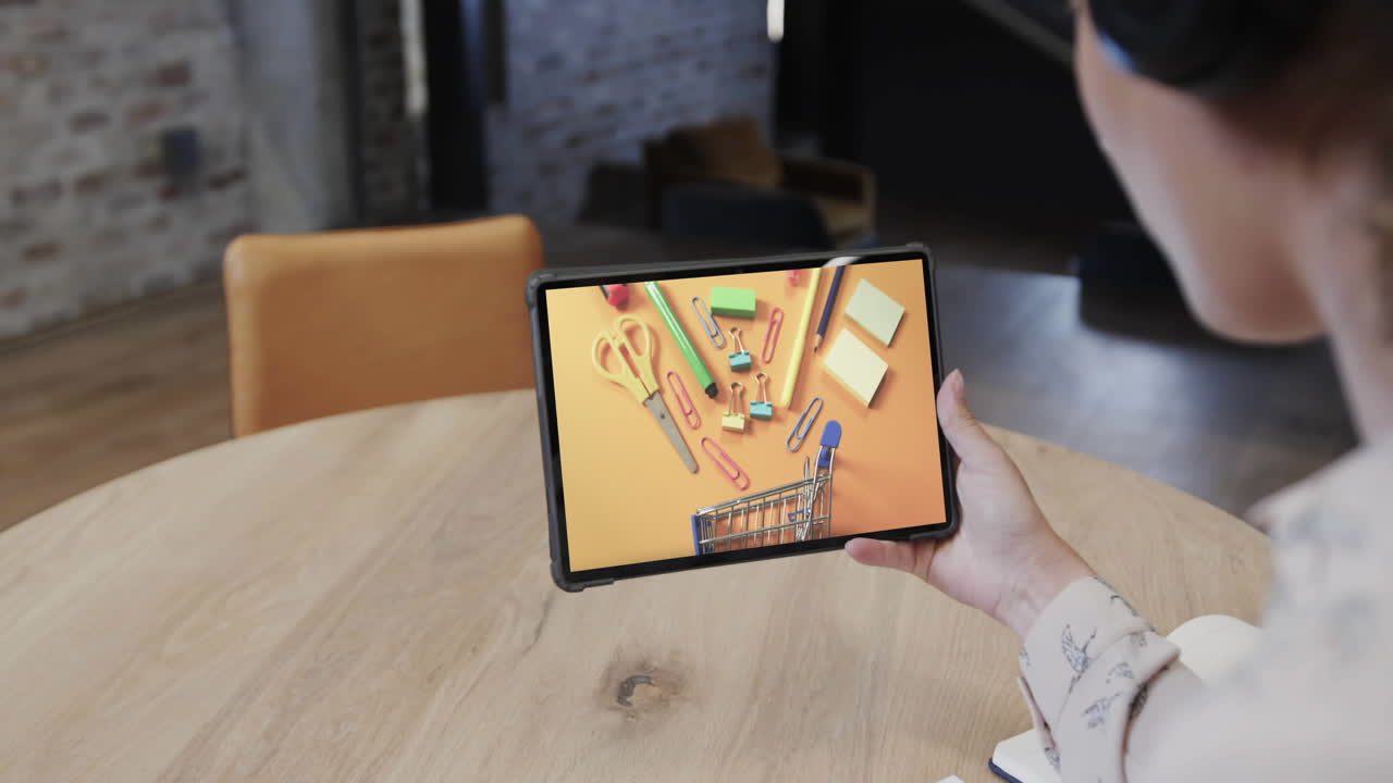 Mulher birracial usando tablet em um café, comprando material de papelaria online, em câmera lenta