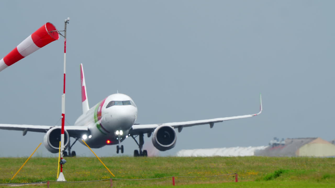 リスボンでウインドソックのそばを離陸するTAPエア・ポルトガルのワイドボディ機