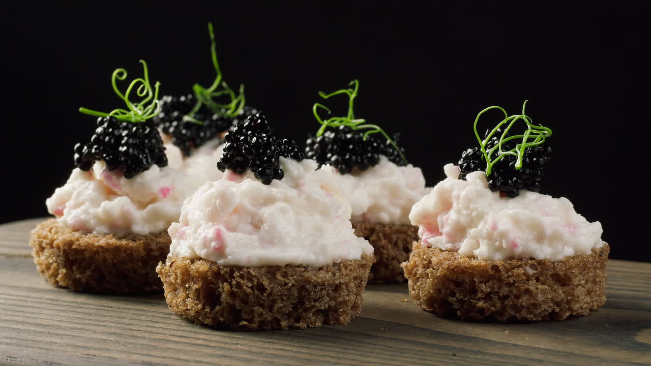 Close-up van zwarte kaviaar die wordt toegevoegd aan gastronomische canapés