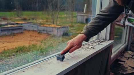 close up of man repairing old wooden window sill