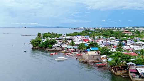 squatted homes on the coastline of surigao city with calm ocean waters, aerial view