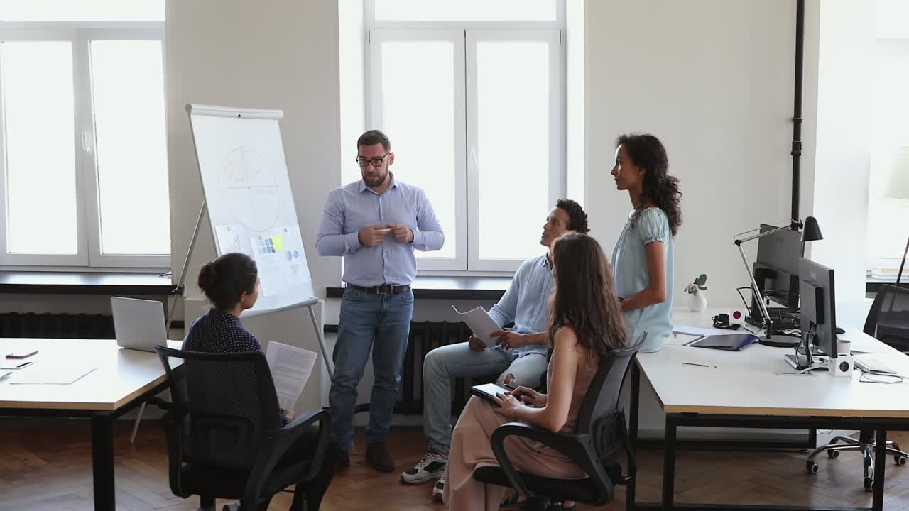hombre de negocios de pie en la pizarra antes de la audiencia multicultural dar clase de negocios