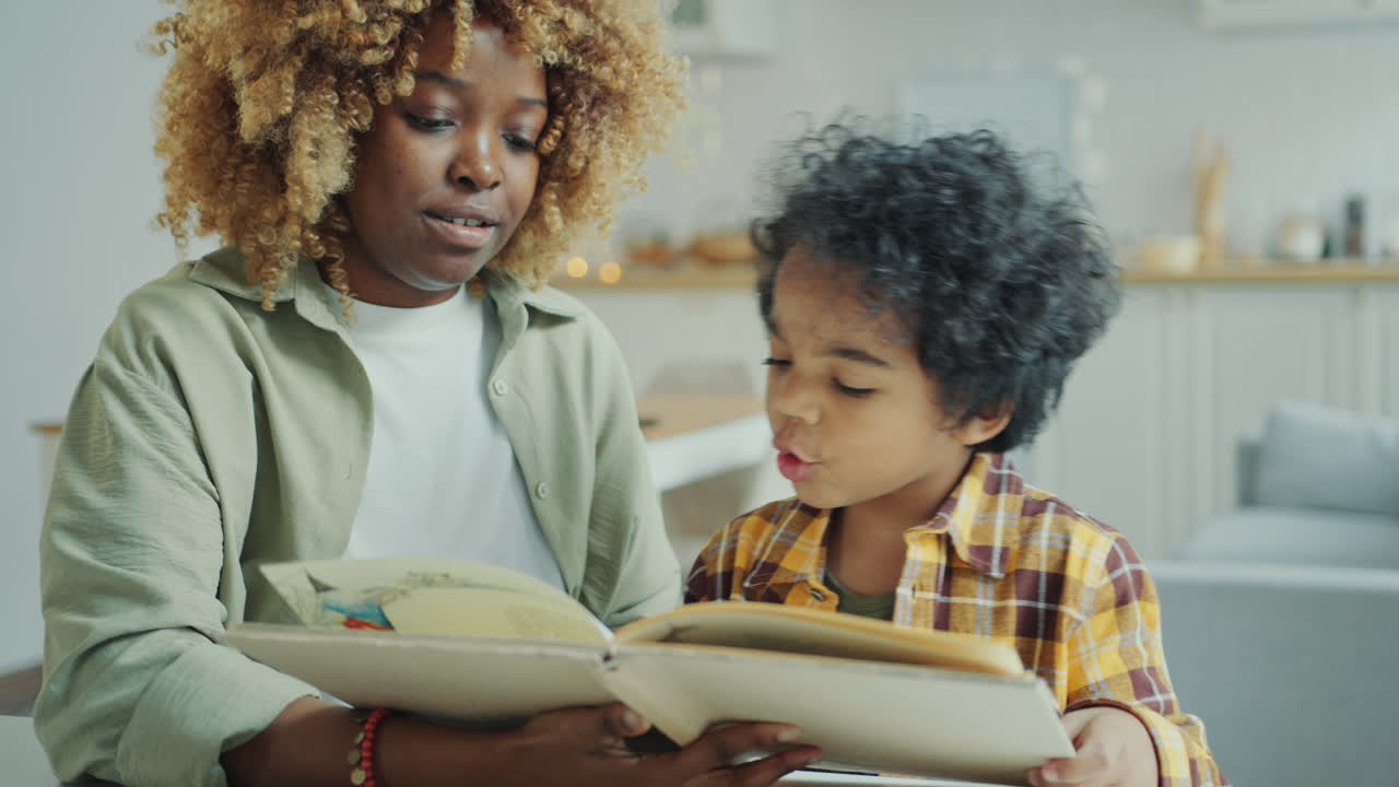 Young Black Mother and Little Son Reading Fairytale Book at Home