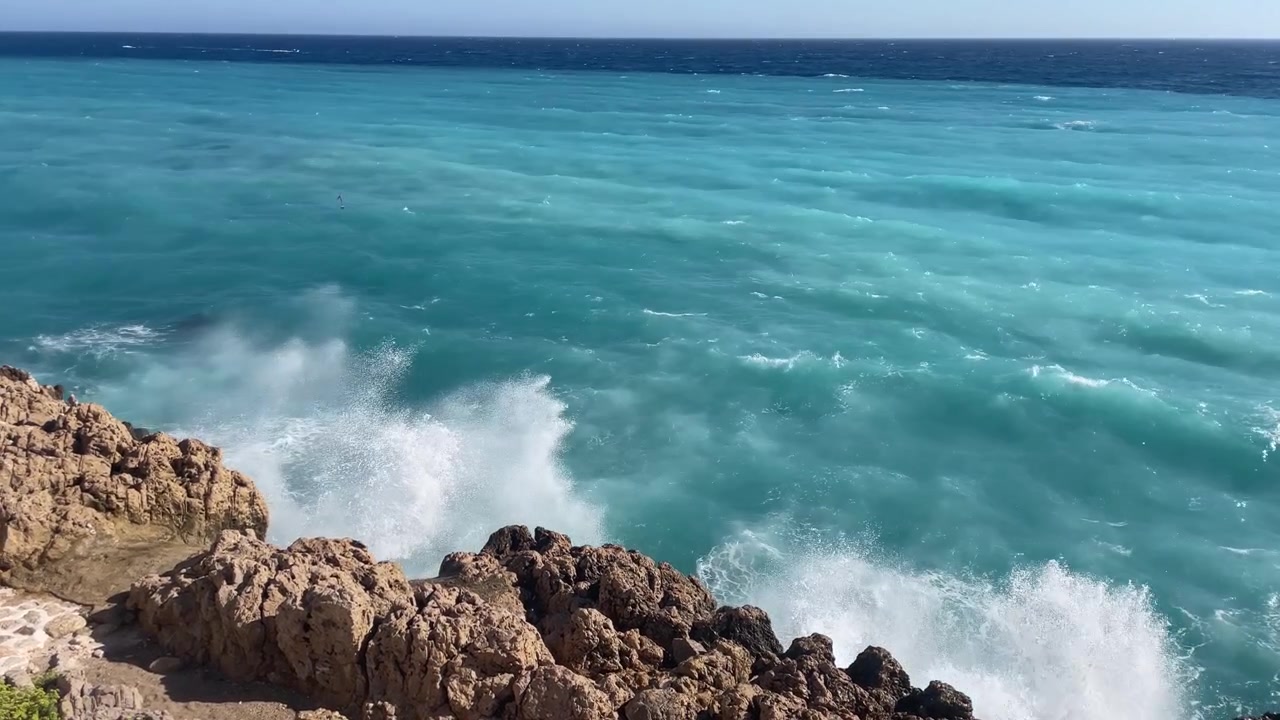 Onde oceaniche turchesi che si infrangono contro una costa rocciosa