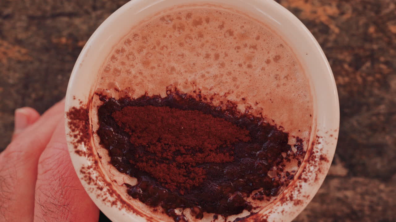 Woman's hand holding a cup of hot chocolate, with cocoa powder visible on top