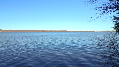 a horizontal pan of a river as seen from the riverbed during a cloudless blue skies type of day