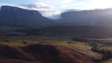 aerial ascent revealing tek river camp and kukenan and roraima tepuis in the background