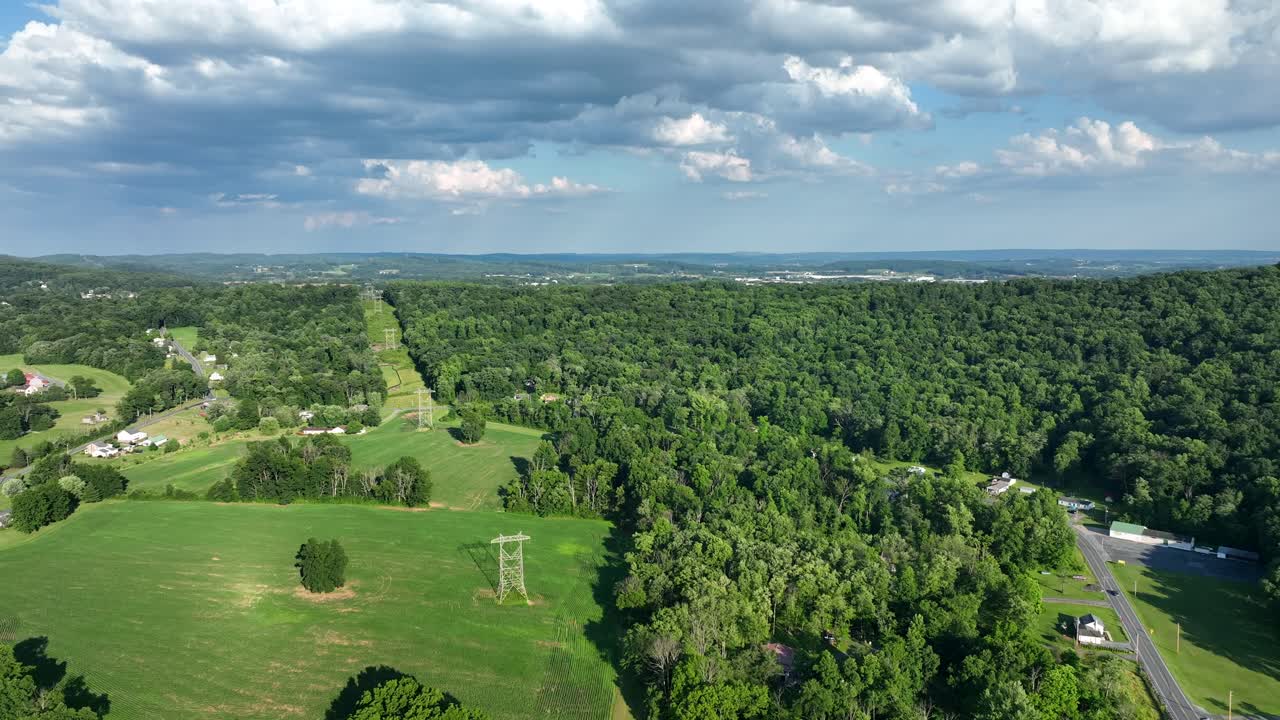 volando sobre el exuberante paisaje rural verde con campos y pequeños grupos de casas en un día soleado