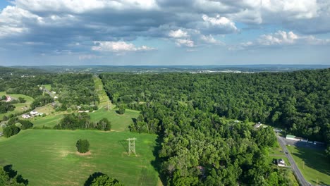 flying over the lush green rural countryside with fields and small clusters of houses on a sunny day