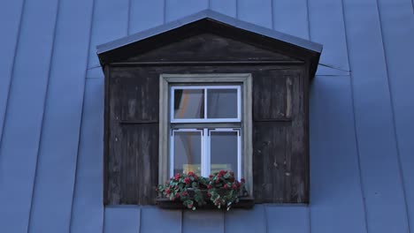 old wooden dormer window with flower box on blue metal roof