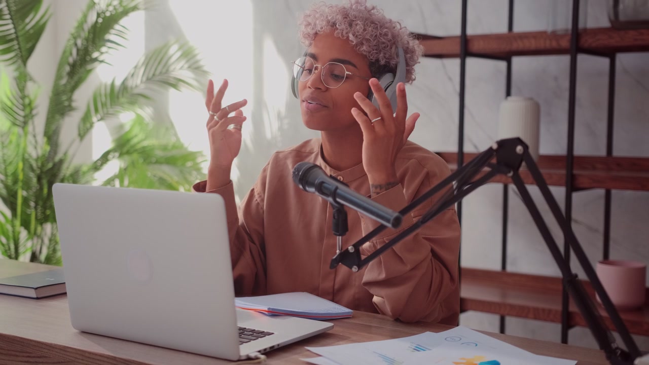 Sort kvinde med blondt krøllet hår tager hovedtelefoner på og starter sit radioprogram.