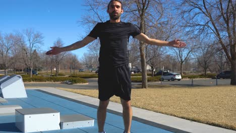 hispanic man with long hair and beard does jumping jacks at park on sunny day