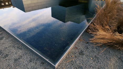 Reflektierender-Pool-Push-in-Zoom-Wolkenreflexion-Auf-Wasser-Mit-Gräsern