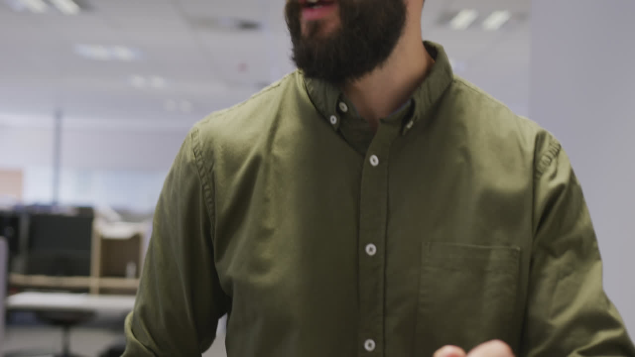 Uomo d'affari caucasico che parla e cammina con lo smartphone in ufficio.