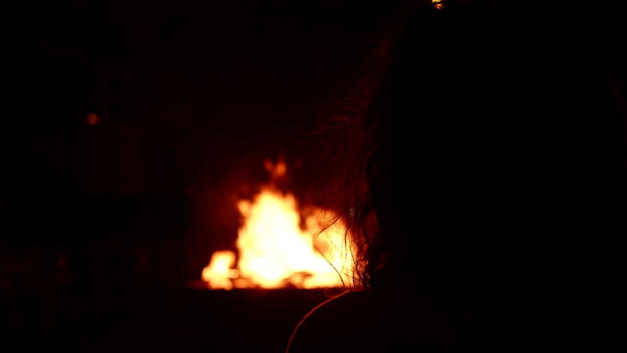 Silhouette di una persona che guarda un falò di notte