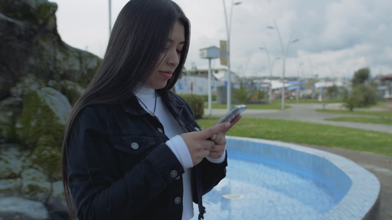 lentamente dando vueltas alrededor de una hermosa joven hispana escribiendo en su teléfono
