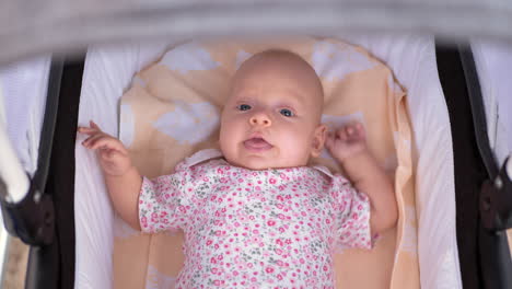 baby girl of three months lying in baby carriage