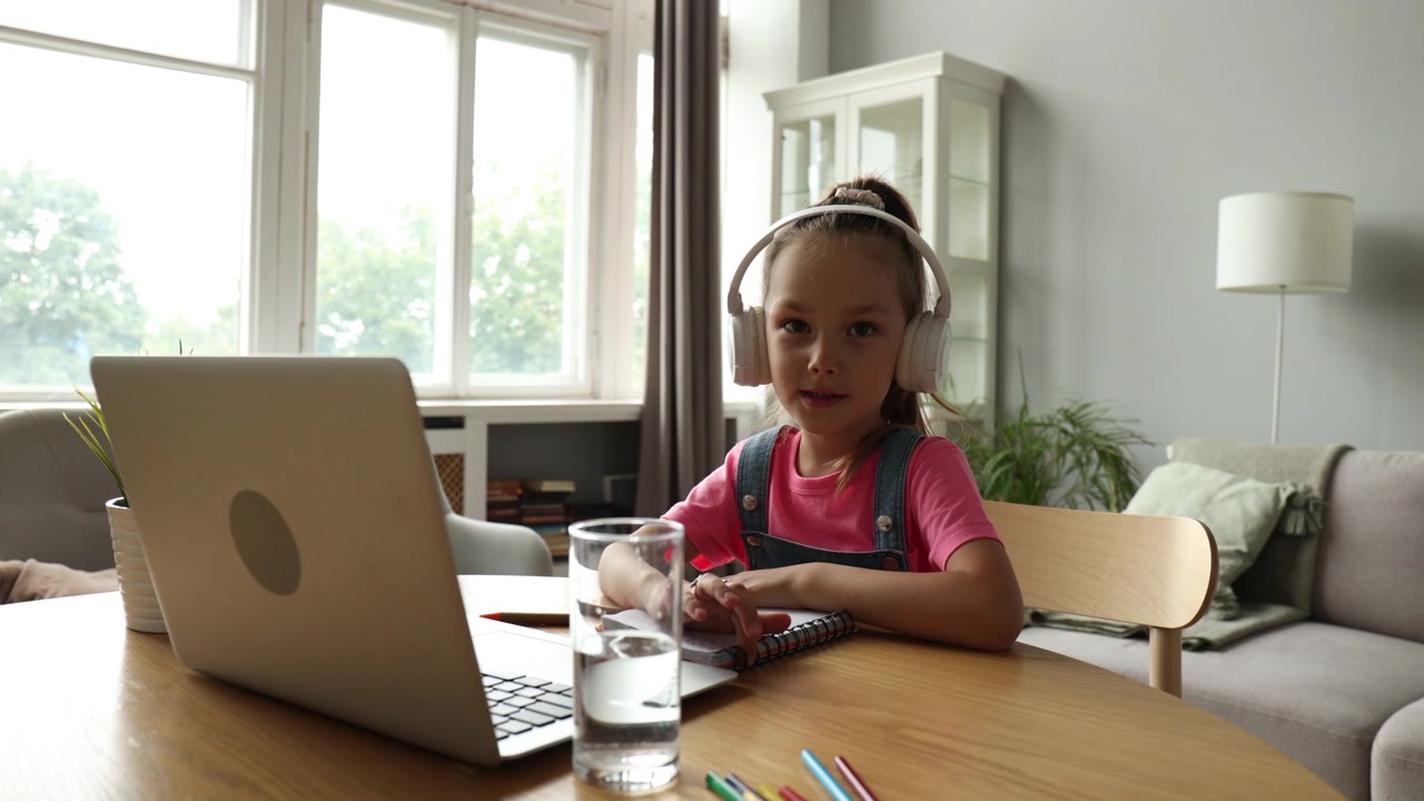 Young Girl in Headphones Engaged in Online Learning at Home