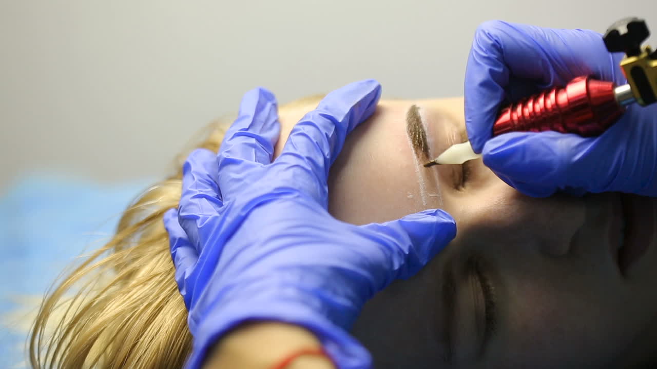 Permanent Brow Makeup. Beautician hands doing eyebrow tattoo on woman face