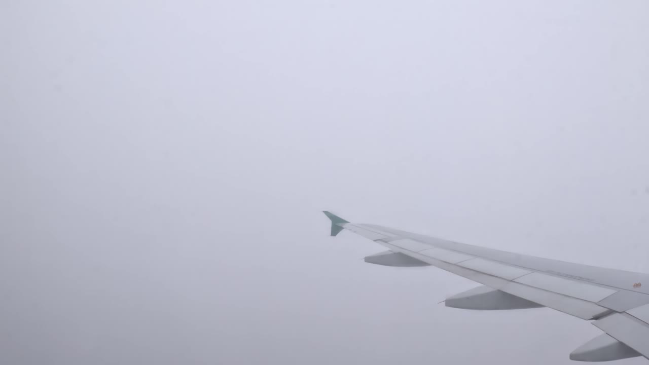 Looking out from the plane, the wing disappears into thick clouds, adding mystery to the flight.