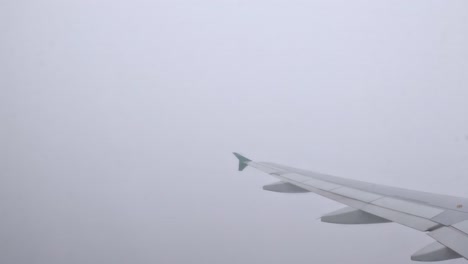 looking out from the plane, the wing disappears into thick clouds, adding mystery to the flight.