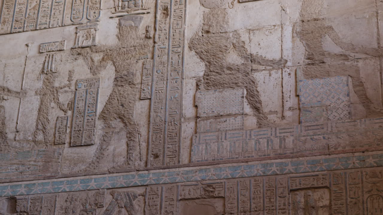 Ancient Egyptian wall relief with pharaohs and faded colors in Dendera, Egypt