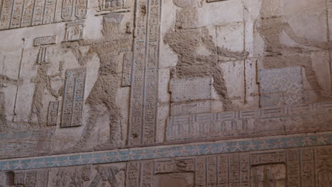 ancient egyptian wall relief with pharaohs and faded colors in dendera, egypt