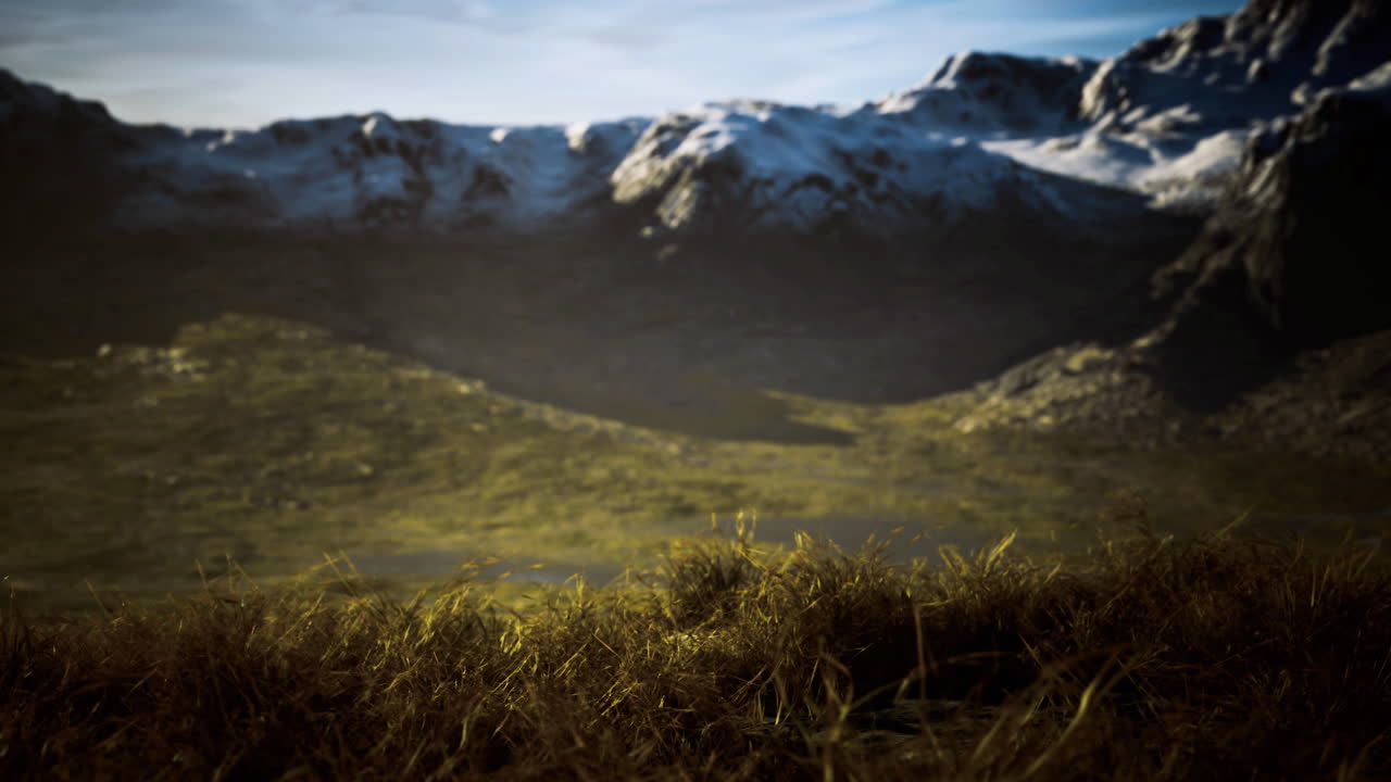 Majestic mountain landscape with snow peaks and green hills at sunset