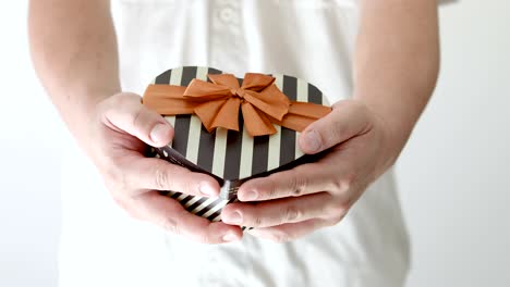 a man holding and giving surprise presents gift box heart shape , congratulation for happy birthday , happy new year, merry christmas, happy valentine's day or anniversary concept , 4k dci resolution