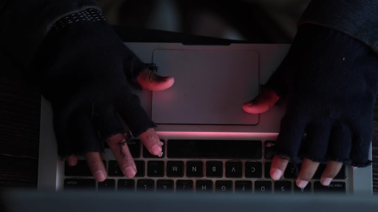 Person Hacking a Laptop in the Dark