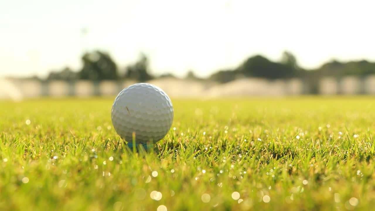 Hånd i hanske plasserer golfball på tee
