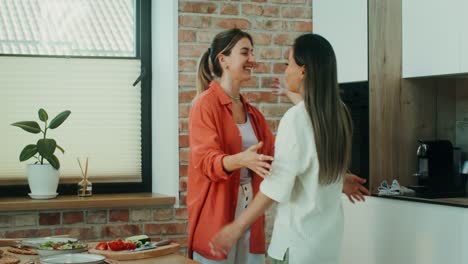 dos amigas abrazándose y hablando en la cocina moderna