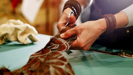 mid-section of craftswoman cutting leather with scissors