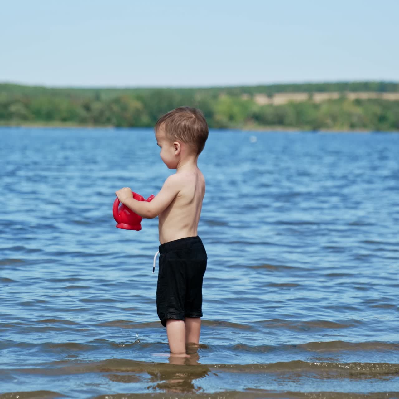 Small funny child playing on river with water. Summer sunny day and splashing on a beach