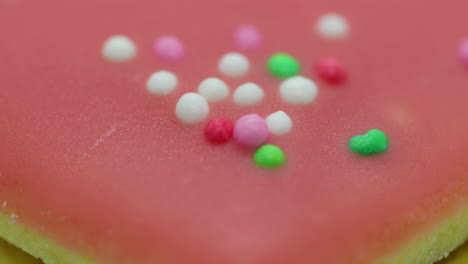 zoom de primer plano mover vista macro de galletas navideñas en forma de corazón rosa con glaseado y decorado con bolas de colores y su corpus en primer plano en captura de cámara lenta