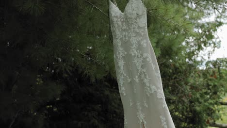 Primer-Plano-De-Un-Precioso-Vestido-De-Novia-De-Diseño-Colgado-De-Un-Pino-En-El-Patio-Trasero-Del-Strathmere-Wedding-Center-And-Spa