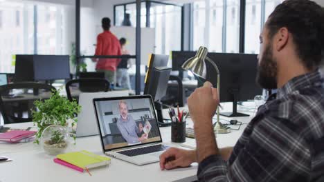 Middle-eastern-man-talking-on-video-call-with-male-office-colleague-on-laptop-at-office