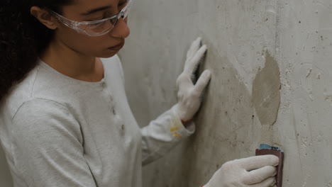 young woman sanding a wall