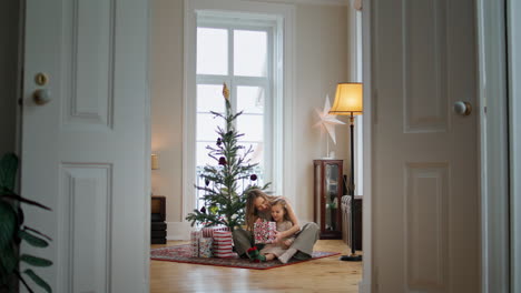 Adorable-Familia-Desempacando-Regalos-Cerca-Del-árbol-De-Navidad.-Tierna-Mujer-Abrazando-A-Un-Niño