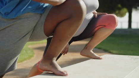 Medium-shot-of-barefoot-friends-stretching-legs-in-public-park