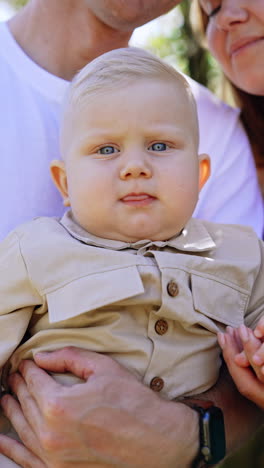 adorable blond serious baby in dad's hands. close up portrait of a child resting with parents. vertical video.