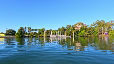 wide daytime shot of nerang river with gentle camera pan, revealing a modern pedestrian bridge, lush greenery, and clear blue sky in gold coast