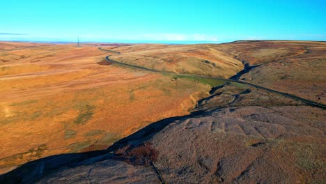 Distant-car-driving-down-a-narrow-country-road-in-the-moors-of-the-UK-with-barron-landscape