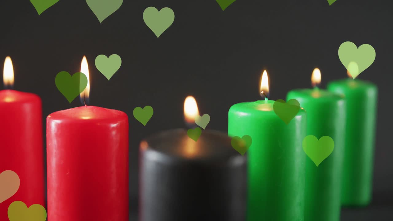 animación de corazones verdes que caen sobre las velas kwanzaa sobre un fondo negro.