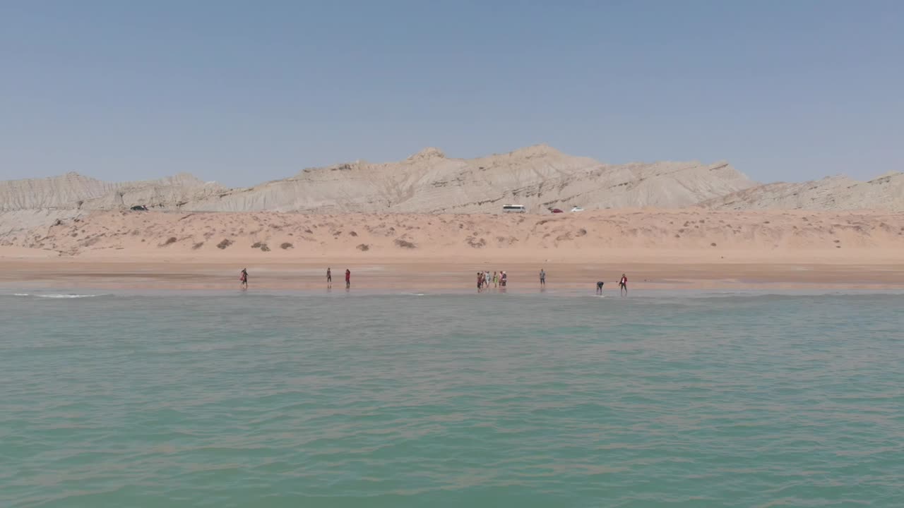 발루치스탄의 황금 해변에서 물속으로 걸어가는 사람들과 함께 바다 위의 공중