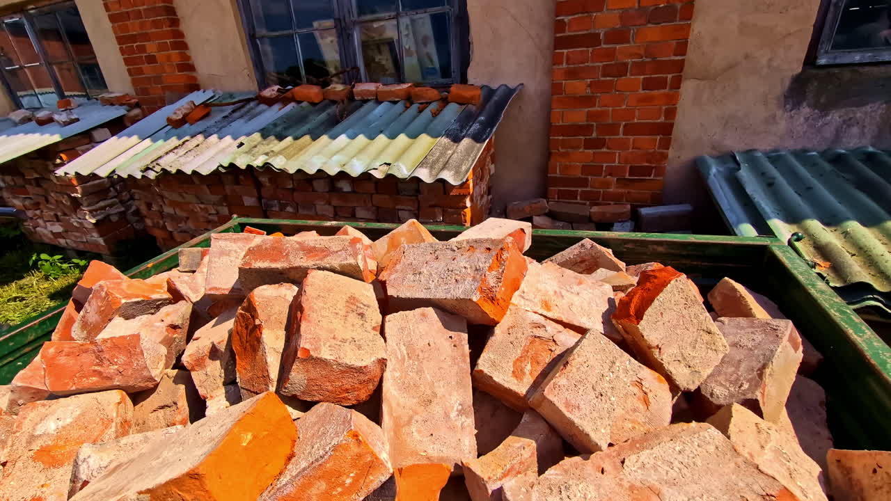 Pile Of Old Red Bricks In Container Under Sunlight With Stacked Bricks Covered With Roof In Background. closeup shot