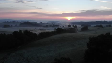 Drone-flying-over-Uchon-countryside-with-sunset-in-background,-France